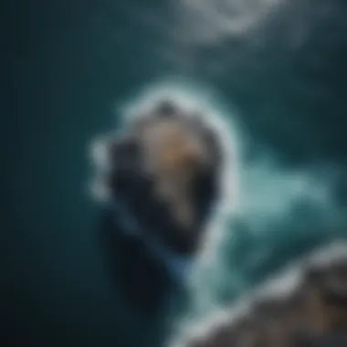 Aerial view of a dramatic black rock formation against the blue sea